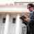 Lawyer in a dark suit and glasses reading a tablet in front of a columned, courthouse-style building
