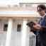 Lawyer in a dark suit and glasses reading a tablet in front of a columned, courthouse-style building